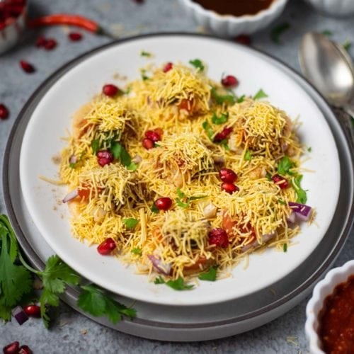 Sev puri street chaat in a white plate with chutneys spread around