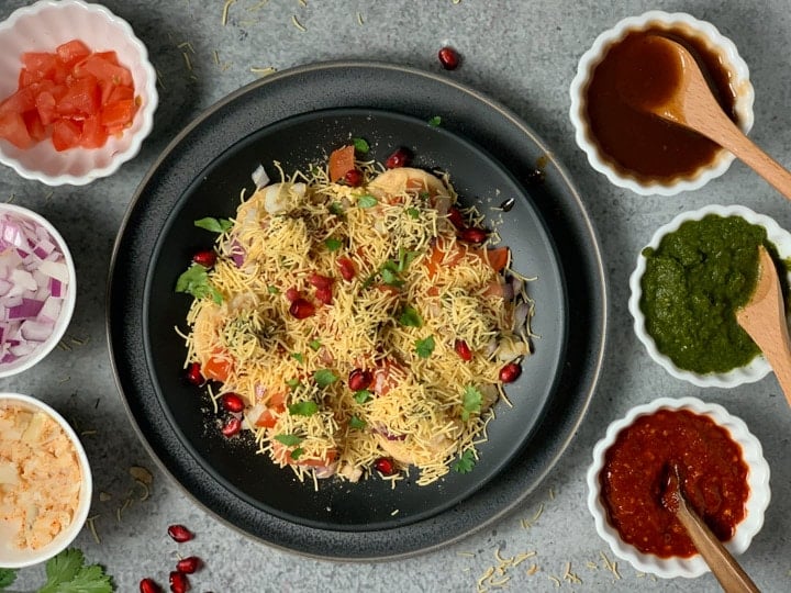 Sev puri garnished with pomegranate and cilantro in a black plate.
