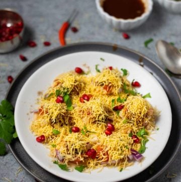 Sev puri street chaat in a white plate with chutneys spread around