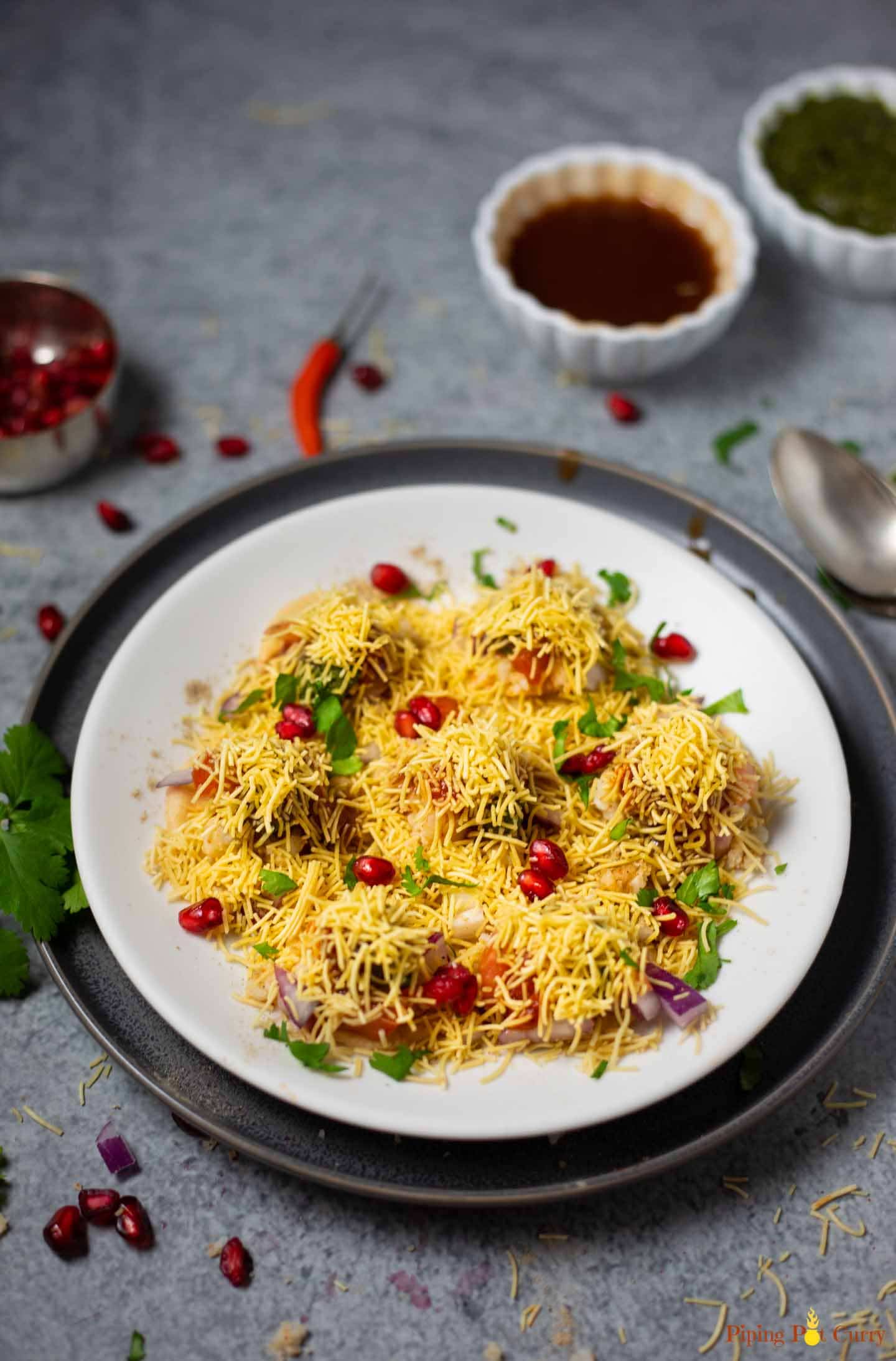 Sev puri street chaat in a white plate with chutneys spread around