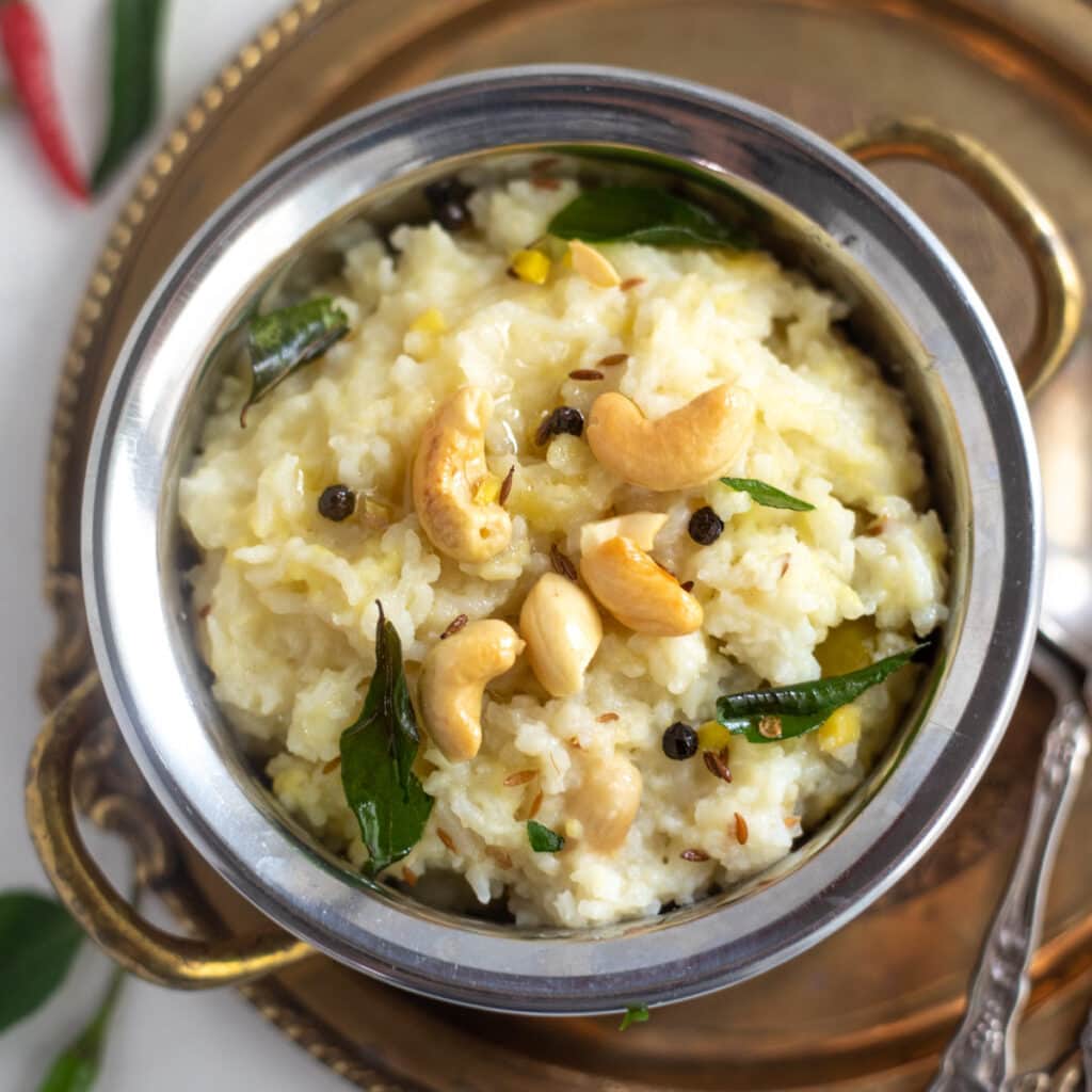 Ven Pongal in a bowl garnished with cashews and curry leaves