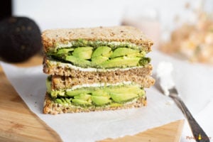 Sandwich with avocado, chutney and cream cheese on a cutting board