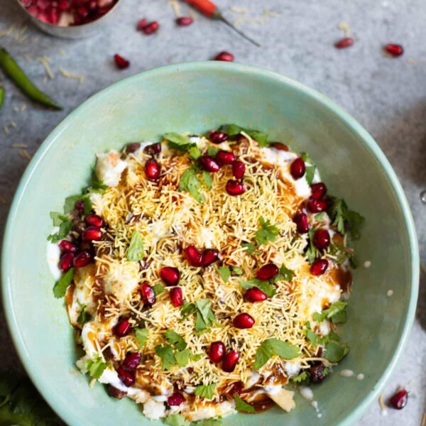 Dahi Papdi Chaat in a bowl with chutneys in the side and pomegranate seeds