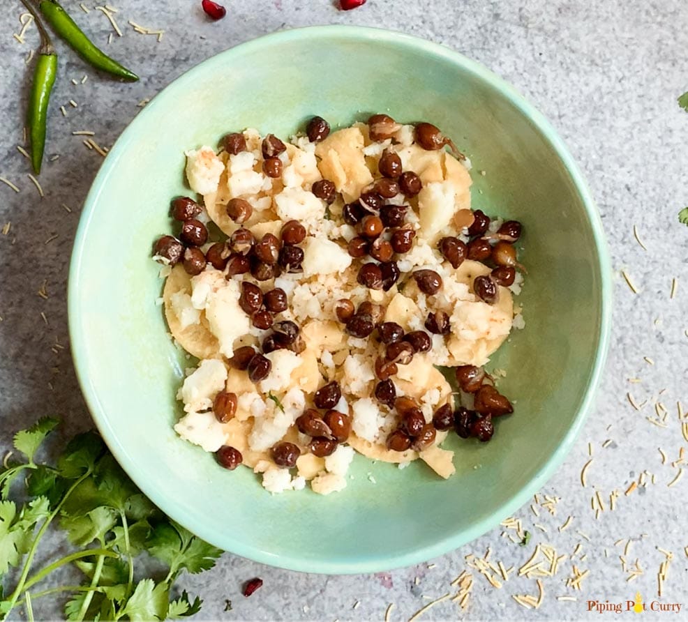 papdi topped with potatoes and black chickpeas in a bowl