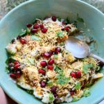 Hand holding papdi chaat street food in a green bowl