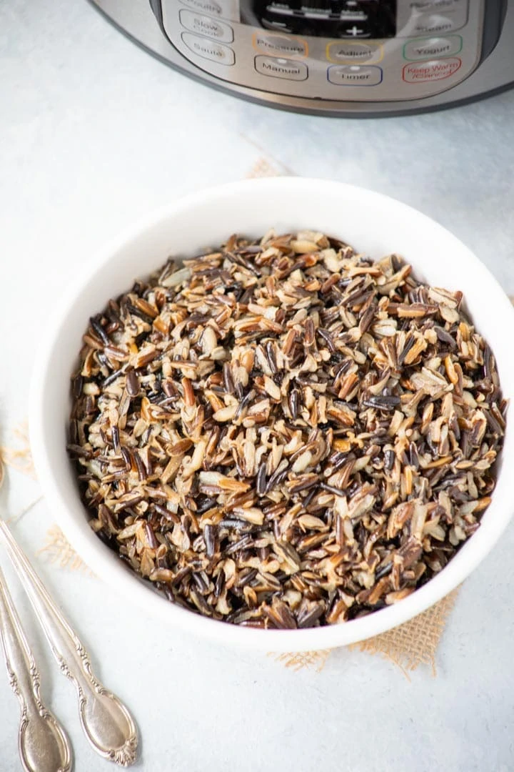 A bowl of cooked wild rice in front of the instant pot