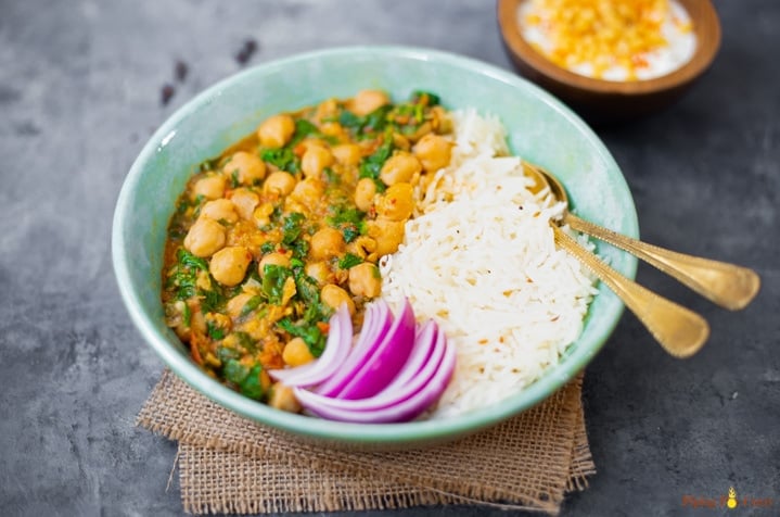 spinach chickpea curry along with rice in a pretty bowl