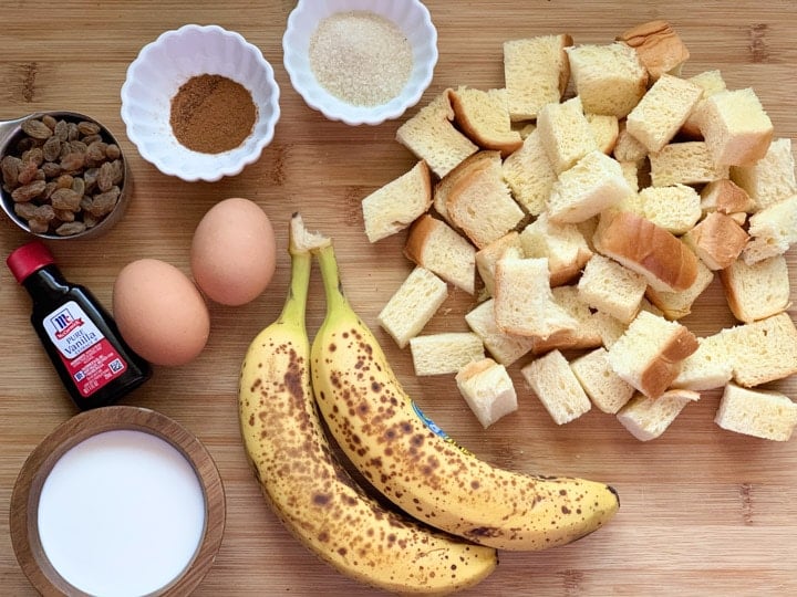 Ingredients to make banana bread pudding on top of a wooden board