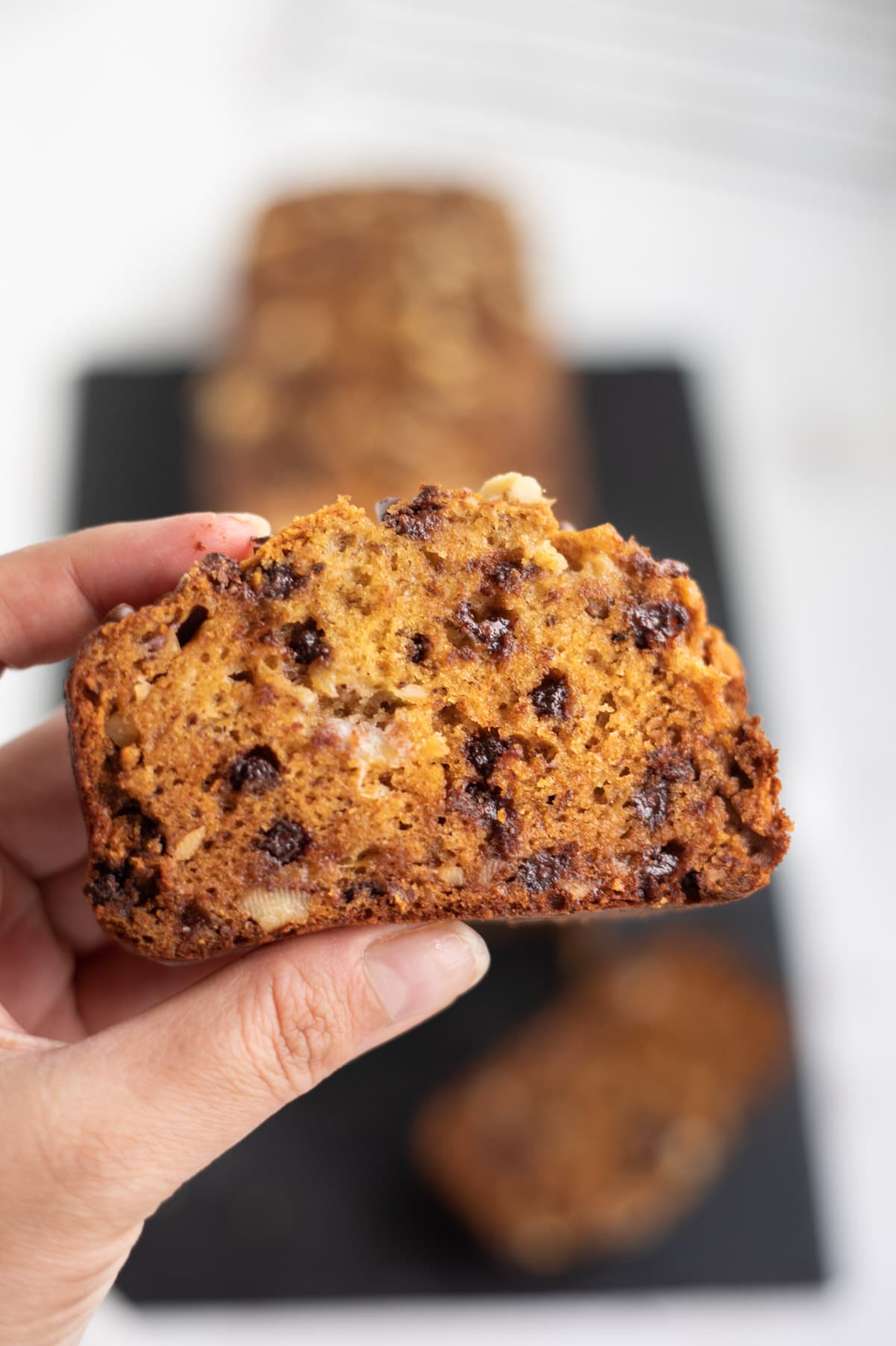 Closeup of One slice of banana bread with chocolate chips and nuts in hand 