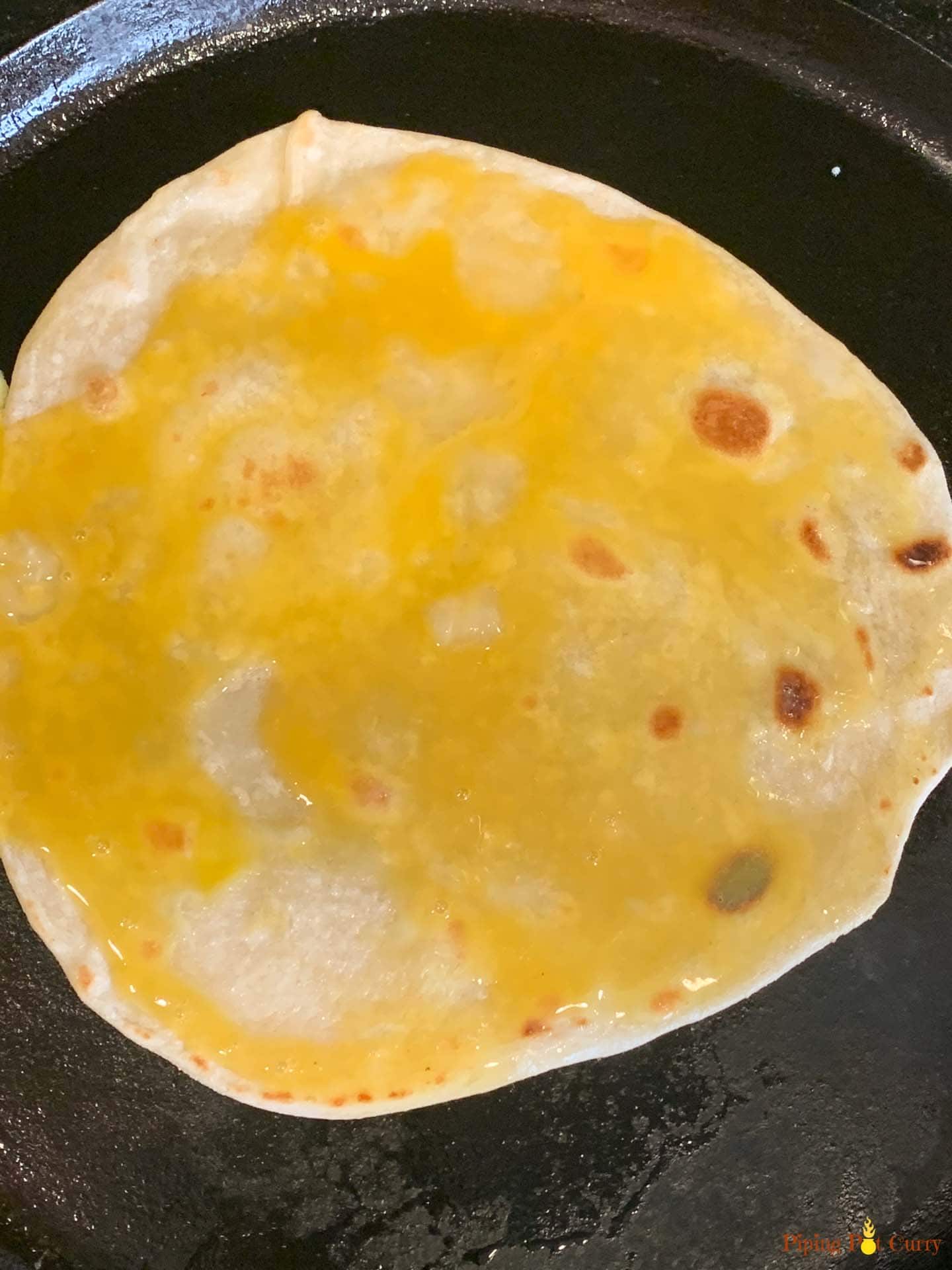 Paneer Kathi Roll - Piping Pot Curry-7 Egg spread on one side of a flatbread on a pan
