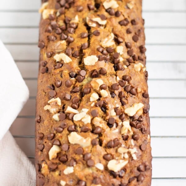 Banana Bread topped with nuts and chocolate chips on a wire rack