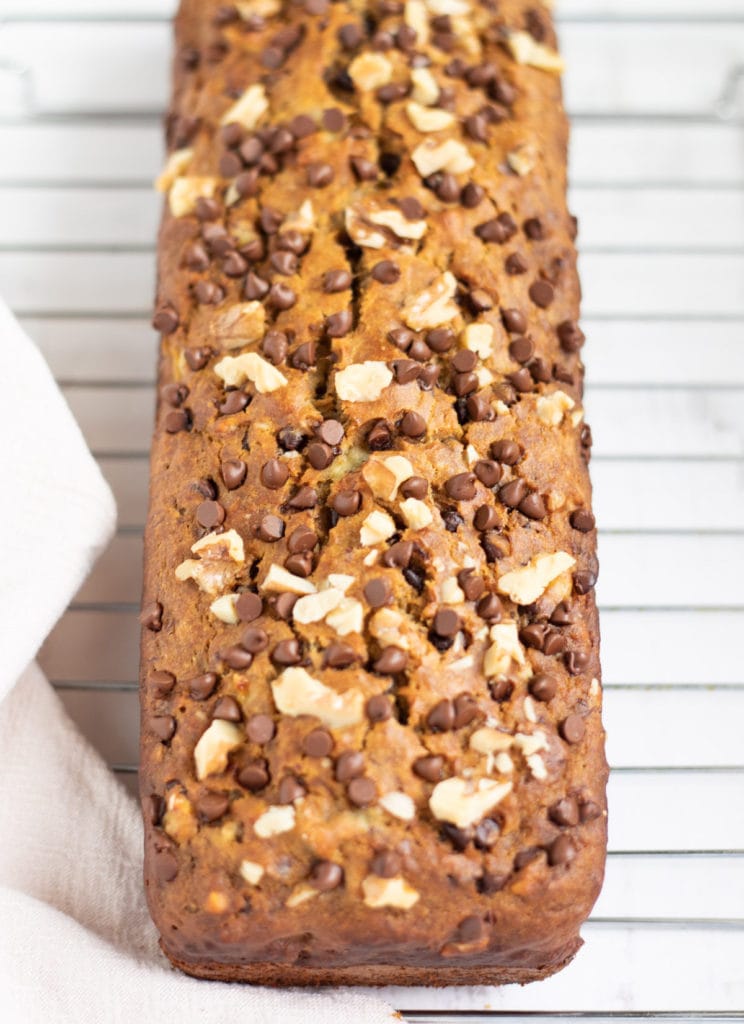 Banana Bread topped with nuts and chocolate chips on a wire rack
