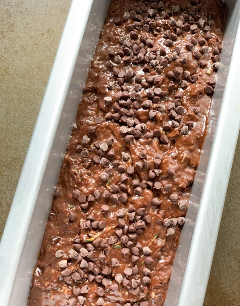 Zucchini bread batter topped with chocolate chips in a loaf pan