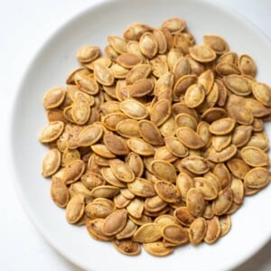 Seasoned roasted pumpkin seeds in a white plate
