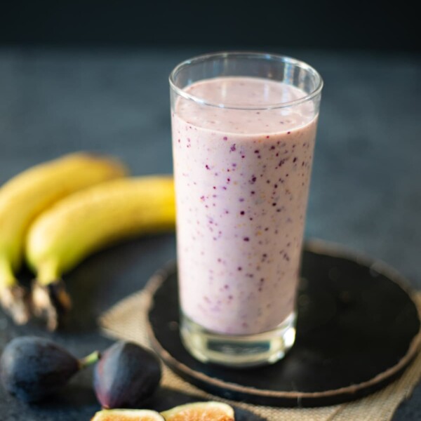 Banana Fig Smoothie in a glass with the ingredients around the glass