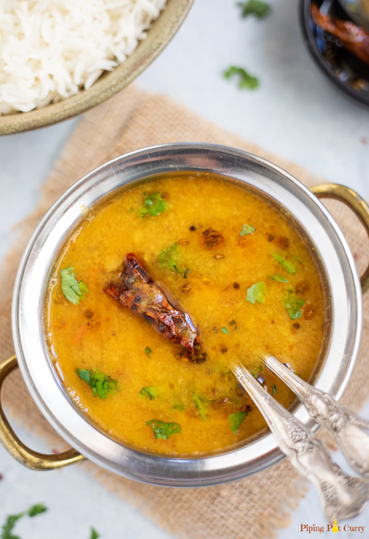 Dal (lentil soup) in a bowl with a red chili tadka and rice on the side 