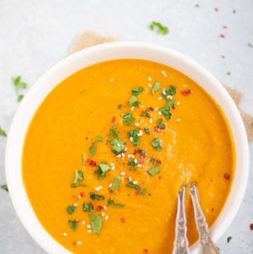 Creamy Carrot Soup garnishes with cilantro, red pepper flakes and sesame seeds