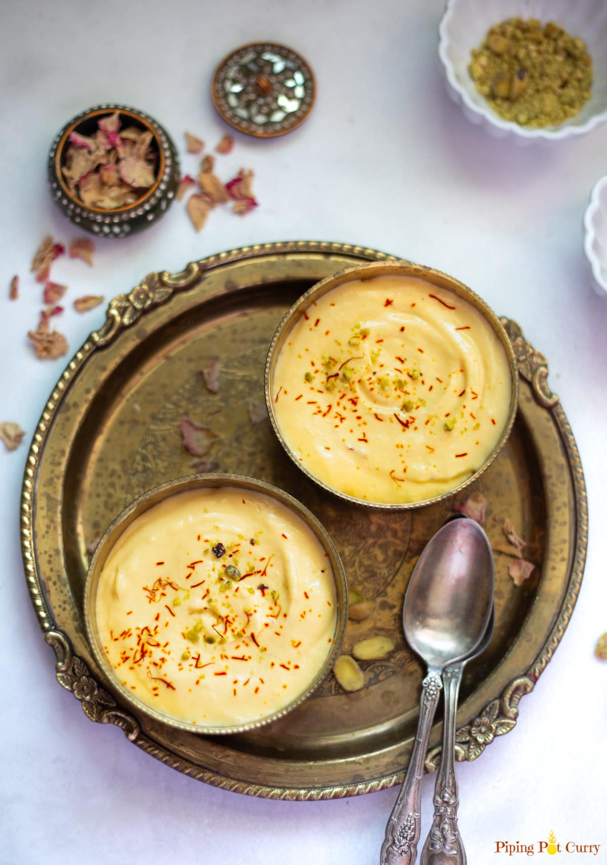 2 small bowls of Indian Mango Shrikhand dessert garnished with saffron and pistachios. 
