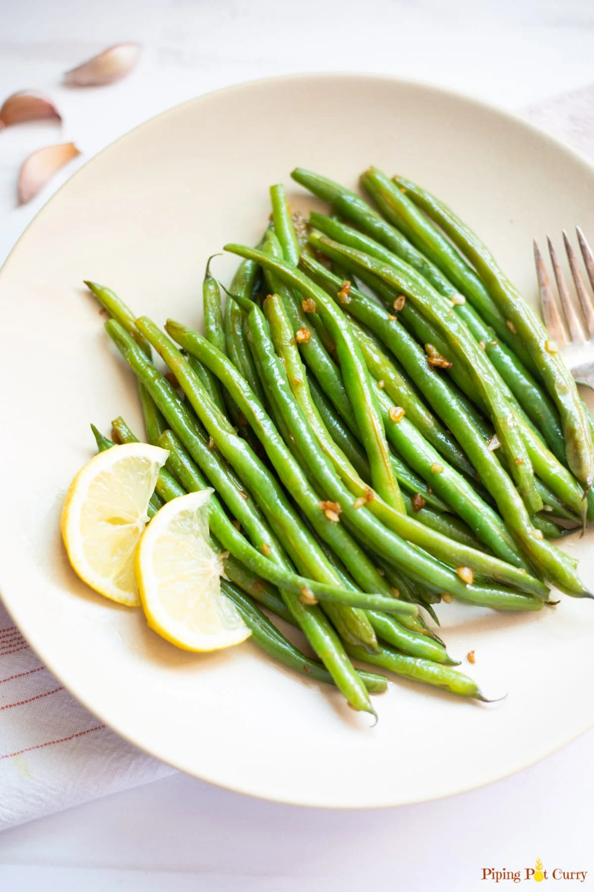 Lemon Garlic Green Beans in a plate with 2 pieces of sliced lemon