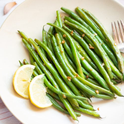 Steamed green beans with garlic and lemon on a platter