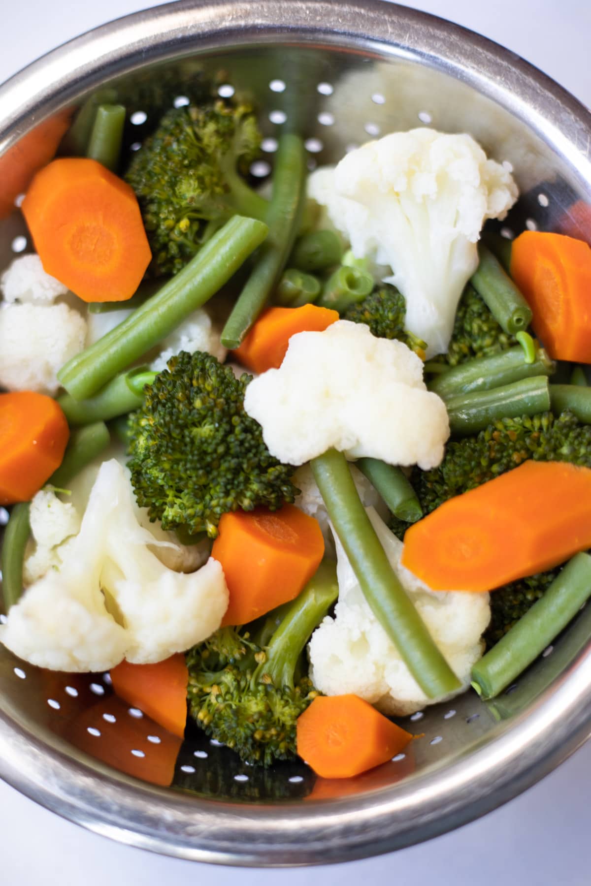 a medley of steamed vegetables in a steamer basket