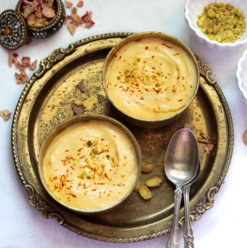 indian mango dessert made with greek yogurt served in 2 pretty bowls