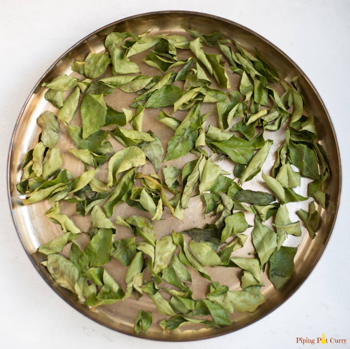 dried curry leaves in a brass plate 