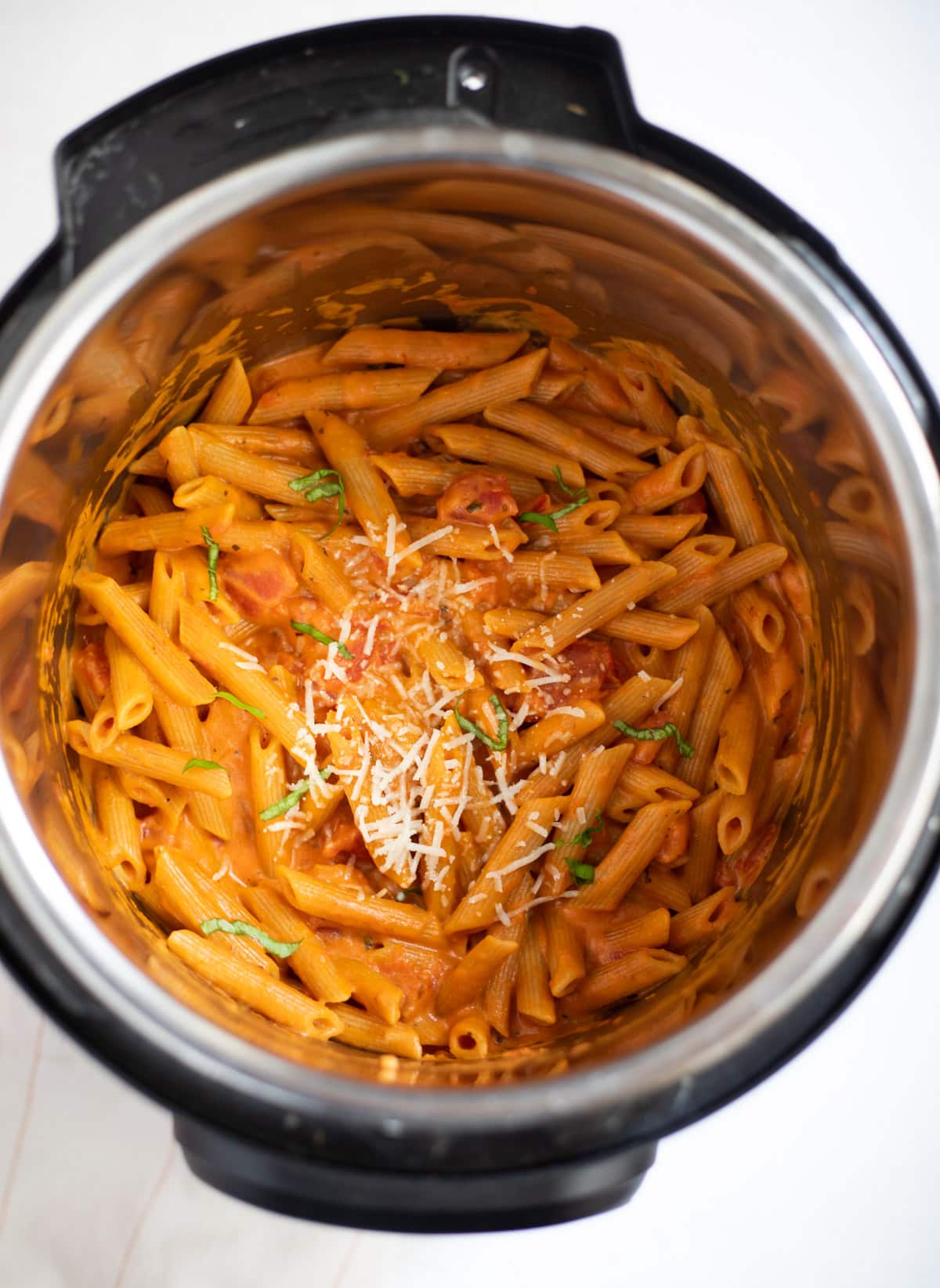 Instant pot Penne Pasta in Tomato Cream Sauce garnished with basil leaves and parmesan cheese