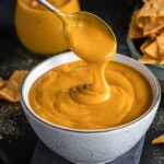 Vegan Chees sauce dripping from the spoon to a bowl.