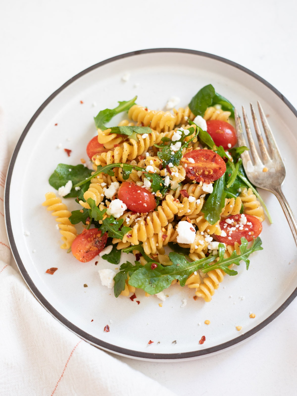 Rotini with arugula and cherry tomatoes topped with feta