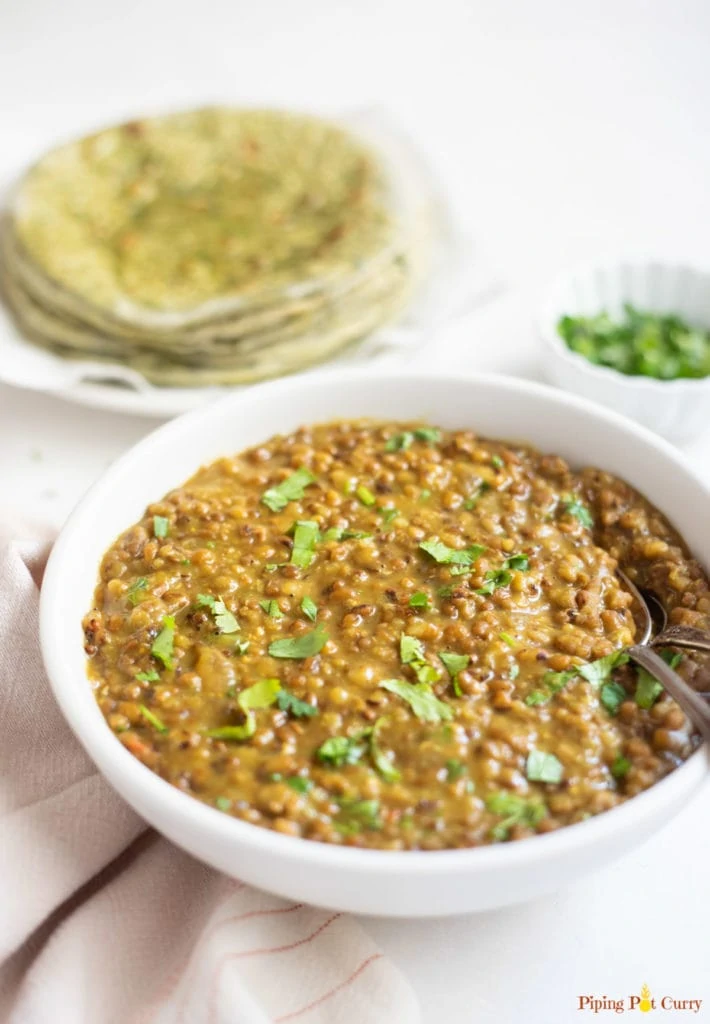 Matki dal in a white bowl garnished with cilantro