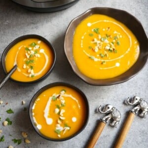 Curried Butternut squash soup topped with coconut milk in front of the instant pot