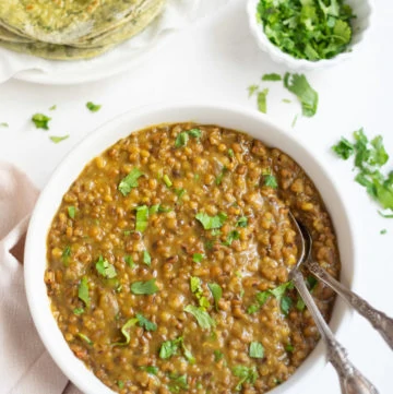 Moth lentils in a white bowl with cilantro and roti