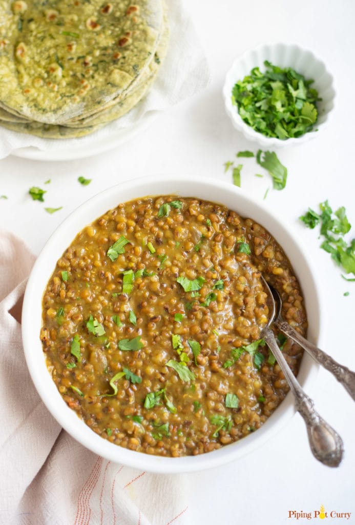 Moth lentils in a white bowl with cilantro and roti 