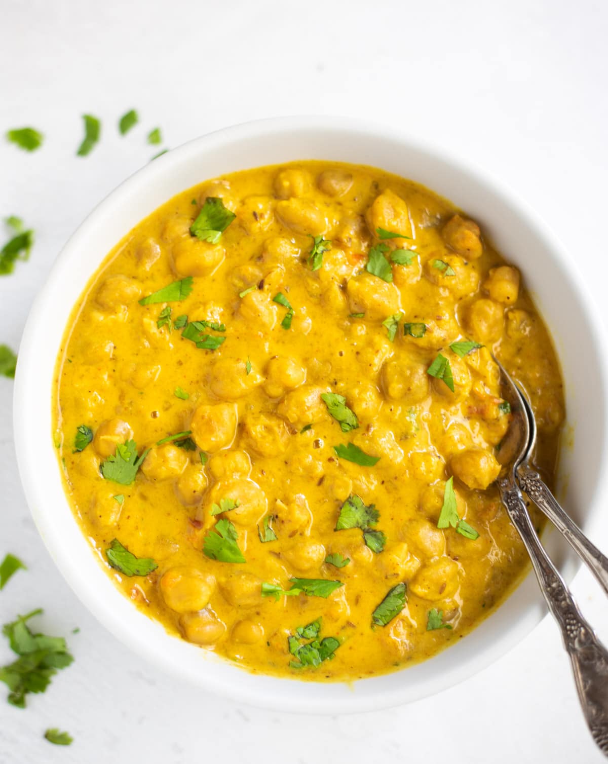 Chickpea curry with coconut milk in a white bowl garnished with cilantro