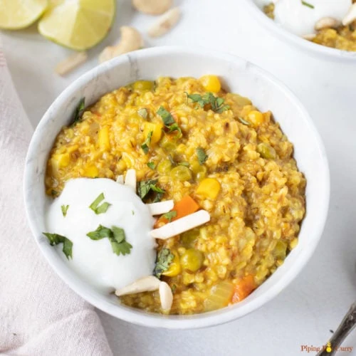 Masala oats with veggies and spices in a bowl along with yogurt
