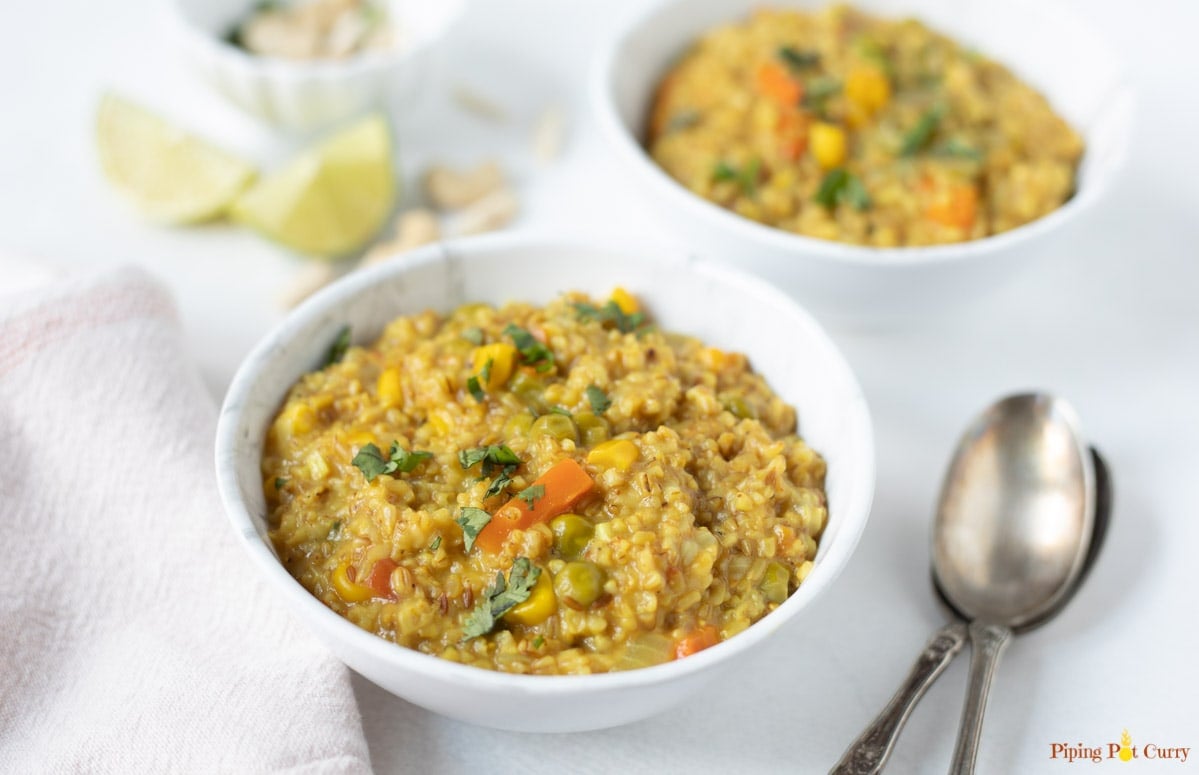 Savory oatmeal with veggies and spices in a bowl with spoon and lemon