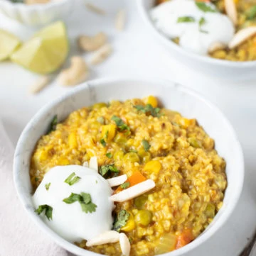 Savory oatmeal with veggies and spices in a bowl along with yogurt