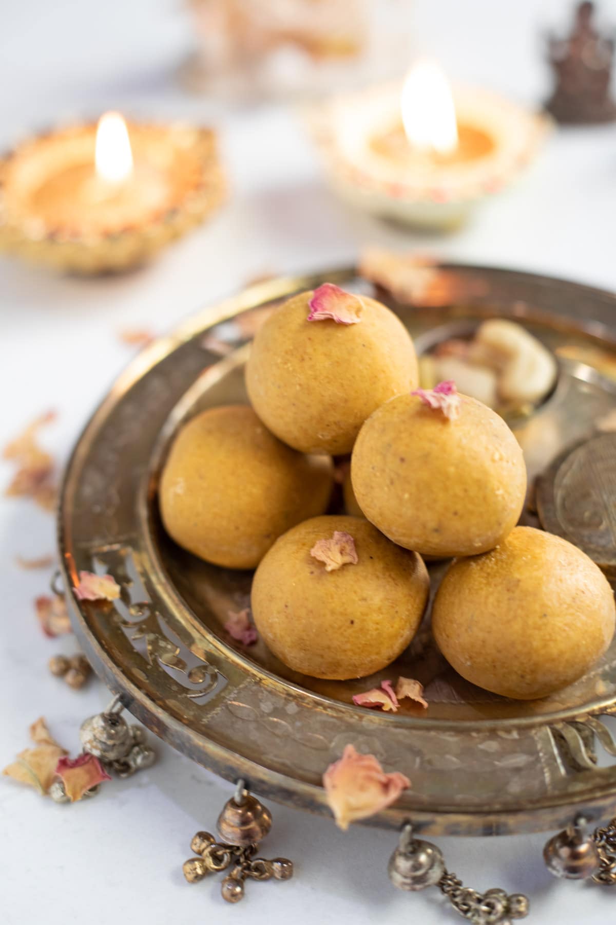 Homemade besan ladoo in a pretty silver plate with Diwali diya's in the back