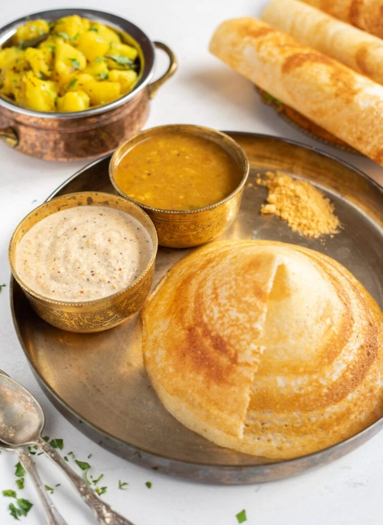 Cone shaped dosa with chutney, sambar and podi in a plate with potato masala on the side