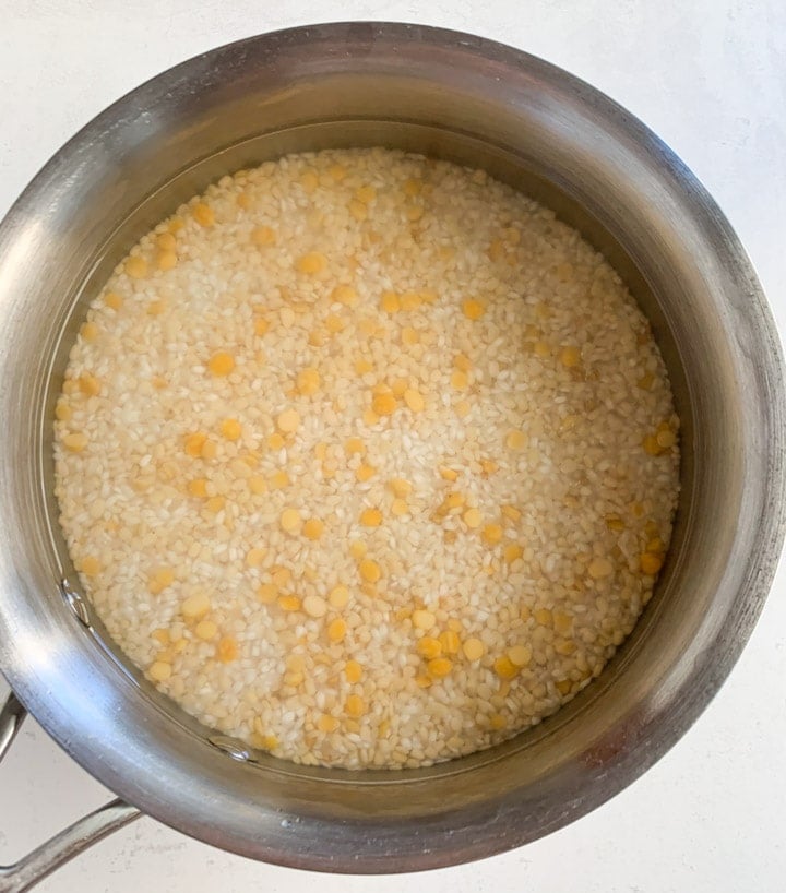 Dosa batter ingredients such as dal and rice soaked in a steel bowl. 