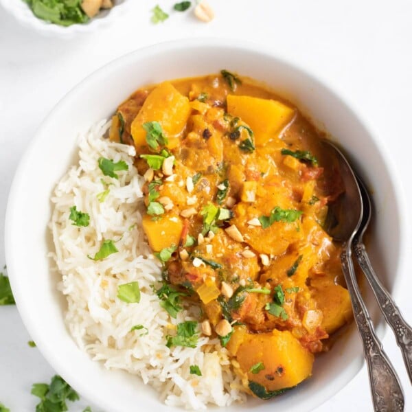 Butternut Squash Curry with spinach served over rice. Garnished with cilantro and peanuts