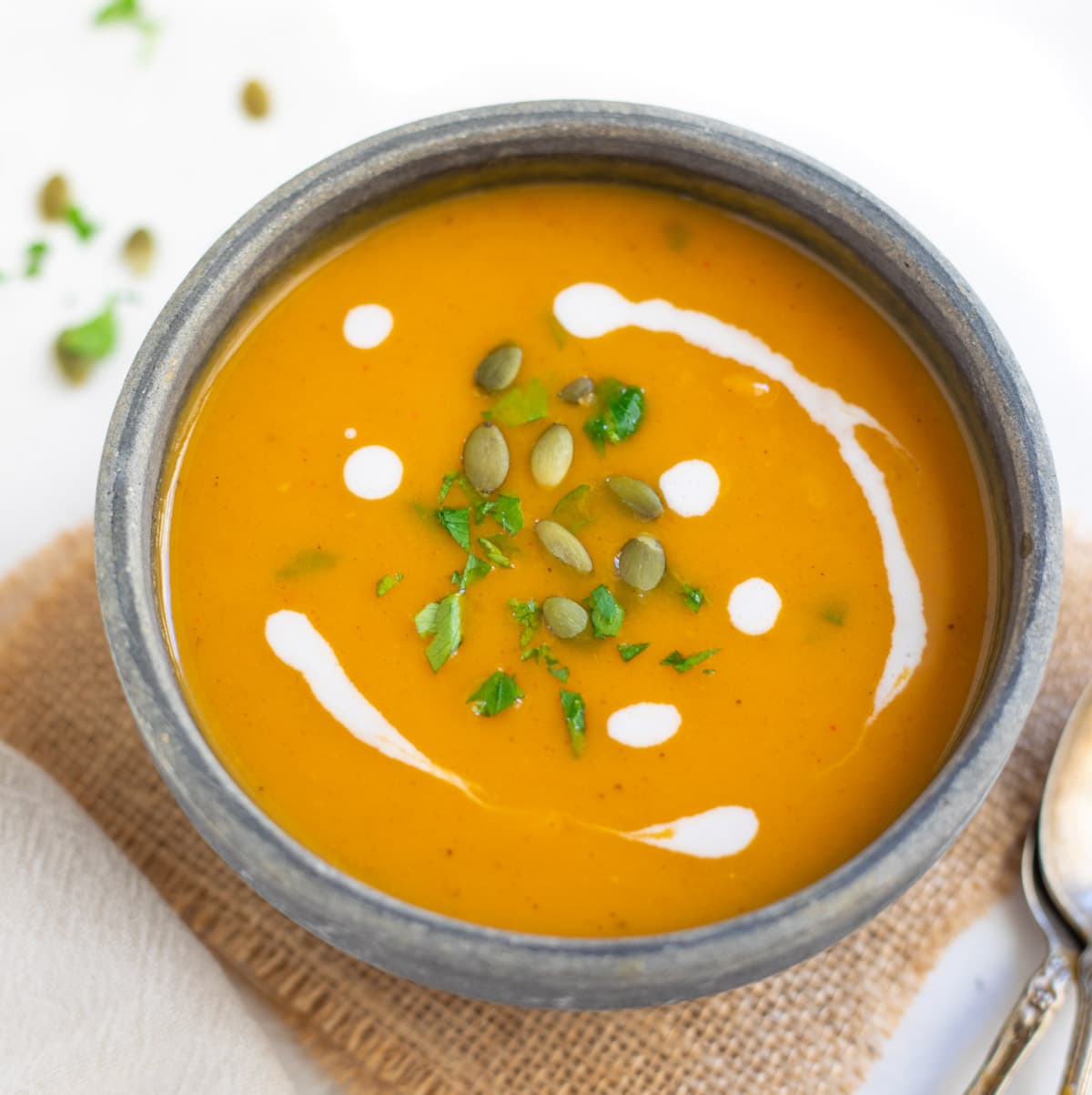 Creamy Sweet potato soup garnished with pepitas and cream in a bowl