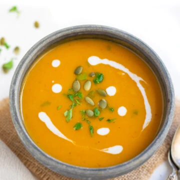 Sweet potato soup garnished with pepitas and cream in a bowl