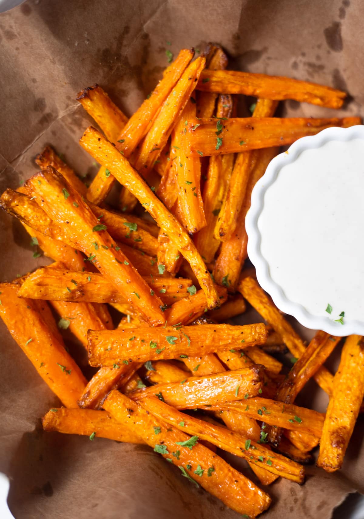 Roasted carrots on a brown paper with a dip