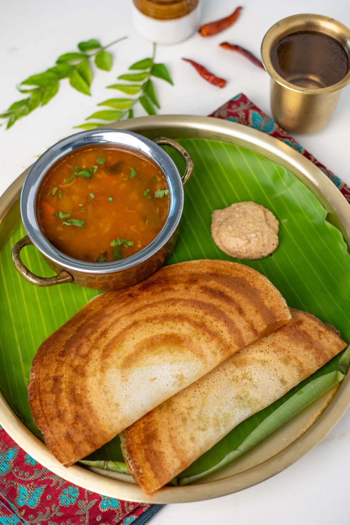 Dosa served with sambar and chutney in a brass plate