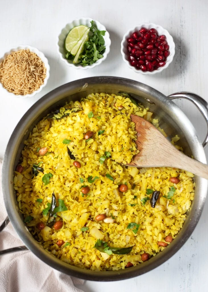 Poha with garnishes of sev, cilantro and pomegranate seeds