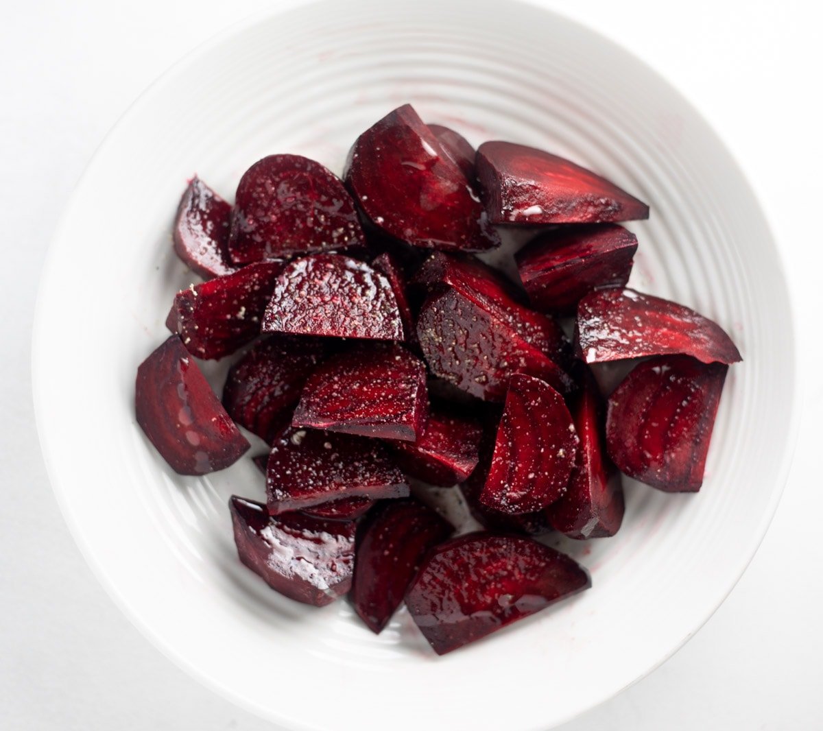 Beet quarters seasoned with oil and salt in a bowl