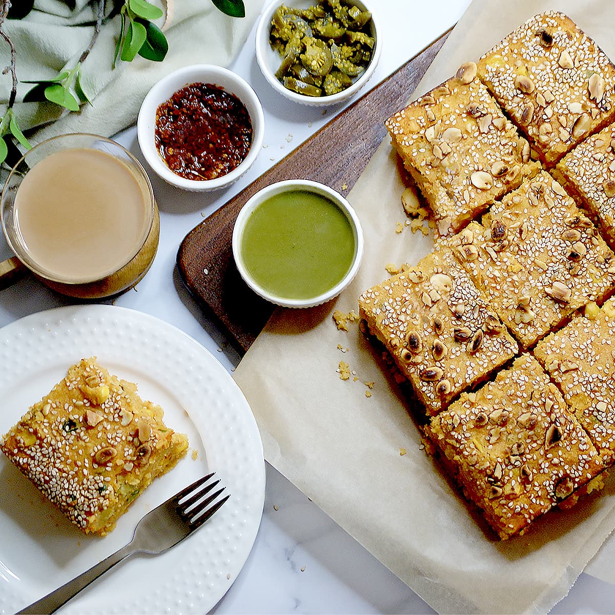 Baked Handvo served on a plate with chutneys and chai