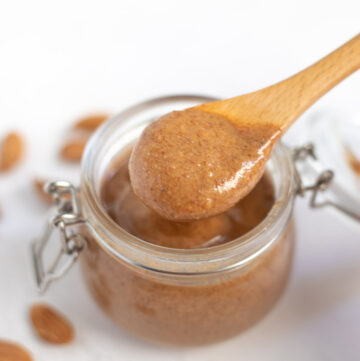creamy almond butter spooned out from a glass jar